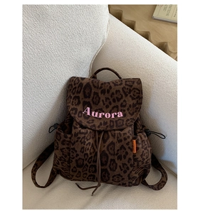 Detail of leopard print backpack with drawstring closure and pink Aurora text on flap