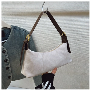 Close-up of beige hobo bag showing suede texture, brown leather strap, and golden buckle