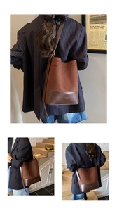 Detail of dark brown suede and faux leather bucket bag featuring a gold brand logo