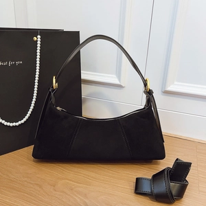 Detail view of black suede shoulder bag with gold metal ring and elegant gift packaging