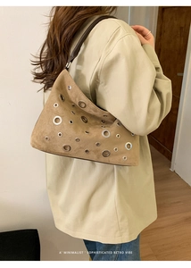 Detail view of retro suede shoulder bag featuring minimalist metallic eyelet patterns