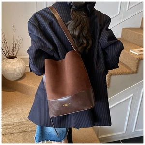 Detail of vintage suede and leather patchwork bucket bag worn on shoulder over a blazer