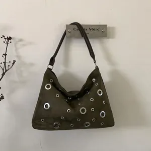 Detail of dark green suede shoulder bag with silver grommets and brown strap