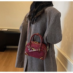 Detail of vintage burgundy Boston bag with suede stitching and metallic horsebit buckle