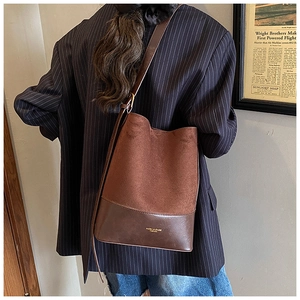 Detail of a large retro bucket bag in brown suede and smooth leather with gold brand logo