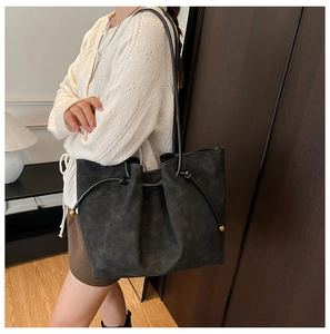 Detail shot of black faux suede tote bag with decorative drawstring and gold hardware