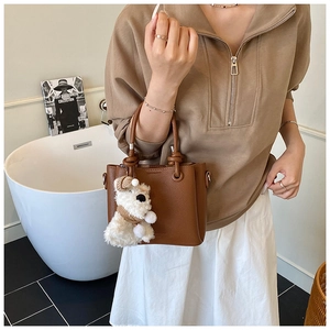 Brown litchi grain leather handbag with a cute white puppy pendant and chic metal rings