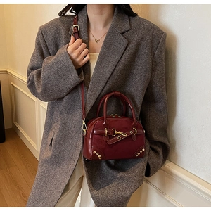 Close-up of vintage burgundy leather handbag featuring gold buckles and adjustable strap
