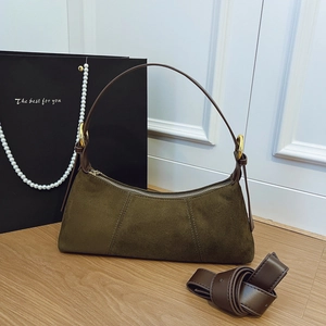Detail of dark brown suede shoulder bag with gold metal rings and extra long strap