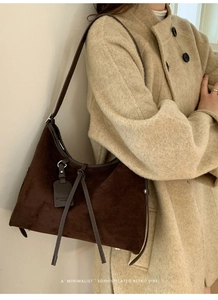 Détail du sac hobo en daim marron foncé avec bordures en cuir et franges décoratives