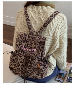 Detail showing leopard print backpack texture with pink Aurora embroidery and drawstring