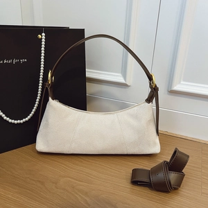 Chic beige hobo dumpling bag with brown leather handles and a long shoulder strap