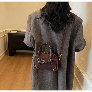 Detail of vintage coffee brown shoulder bag with metal hooks on a female model