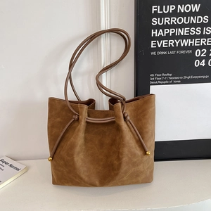 Detailed close-up of dark caramel tote bag with decorative drawstrings and gold bead accents