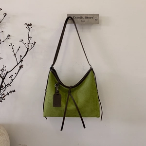 Gros plan du sac hobo en daim vert avec bordure en cuir marron et nœud décoratif