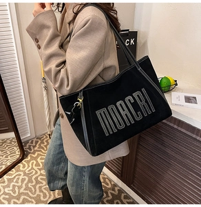 Detail of black large capacity tote bag with white contrast stitching and MORCRI text