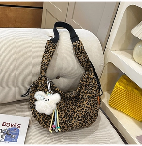 Détail du sac croissant à motif léopard avec pendentif ours blanc et bandoulière réglable