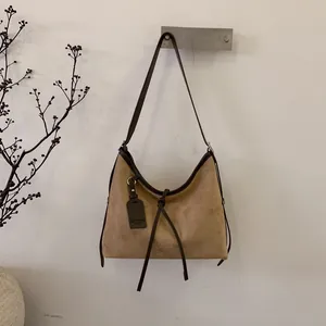 Vue détaillée du sac hobo en daim kaki avec bordures en cuir marron et anneau métallique