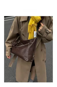 Detail of vintage brown leather crossbody bag featuring white topstitching and side pouch