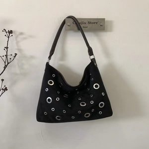 Close-up of matte black suede Hobo bag with silver metal eyelets and dark brown leather handle