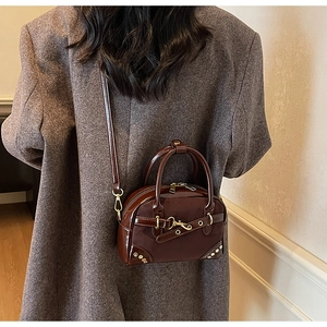 Detail of vintage brown crossbody bag with gold buckle on tweed jacket background