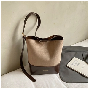 Detail view of khaki suede bucket bag with contrast leather bottom and adjustable strap
