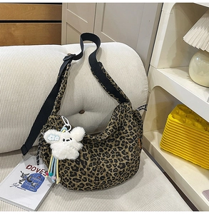 Détail du sac fourre-tout en toile imprimé léopard avec une peluche blanche sur un canapé