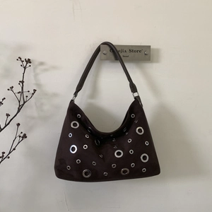 Close-up of retro dark brown suede shoulder bag with decorative silver metal eyelets