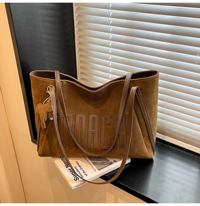 Detail of brown suede tote bag with MOACK embossed logo and cute elephant charm