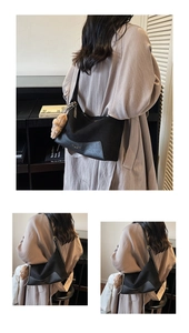 Close-up of black vintage hobo bag with teddy bear charm and sleek minimalist hardware