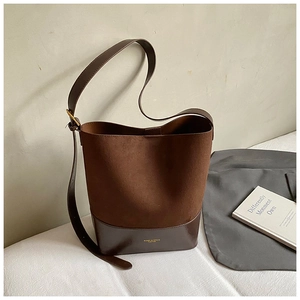 Detail of the brown suede and leather bucket bag featuring a gold logo and adjustable buckle