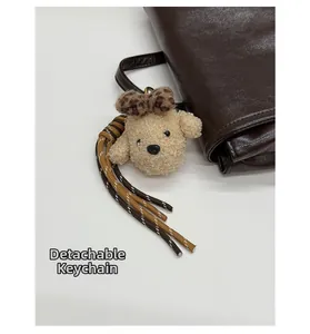 Detail of detachable plush dog charm with leopard bow on a leather backpack
