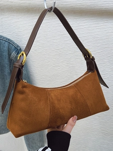 Brown faux suede underarm bag with crescent shape and adjustable leather strap