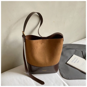 Detailed view of bicolor suede bucket bag with gold logo and smooth brown leather trim