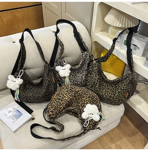 Collection de sacs croissants en toile léopard avec pendentifs en peluche sur un canapé