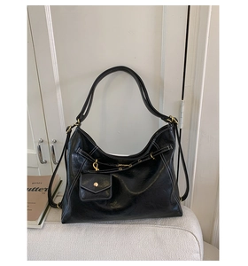 Detail of black faux leather tote bag with white contrast stitching and gold hardware