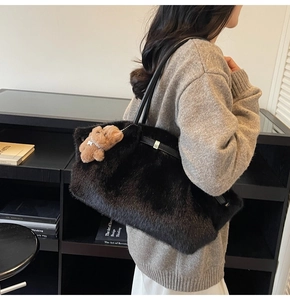 Dettaglio della borsa tote in peluche nera con manici in pelle e ciondolo a orsetto
