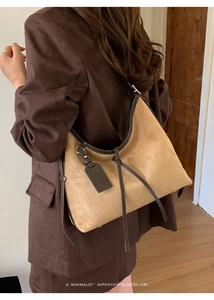 Détail du sac à bandoulière en daim avec bordure en cuir marron et étiquette de logo