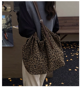 Detailed view of leopard print tote bag with brown leather strap worn by a model in autumn