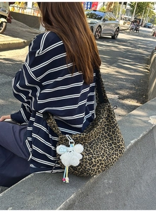 Gros plan du sac en toile léopard avec un pendentif peluche et une bandoulière