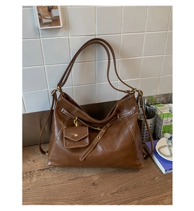 Detailed view of a vintage brown leather tote bag with contrast stitching on a wooden table