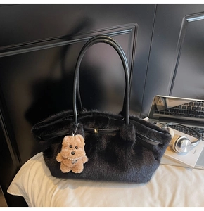 Dettaglio borsa tote in ecopelliccia nera con ciondolo a forma di orsetto e manici in pelle