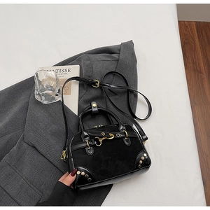 Close-up of black retro Boston bag with gold rivets and leather textures on a grey blazer