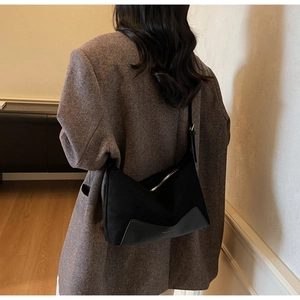 Detail of a black hobo shoulder bag in faux suede worn with a vintage brown blazer