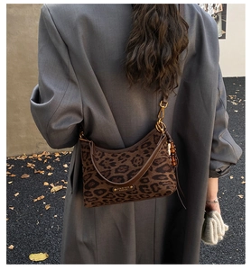 Detail of leopard print shoulder bag with beaded charm and metal logo plate