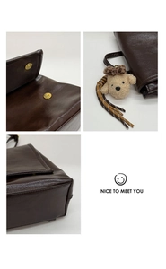 Detail of dark brown vintage backpack with gold magnetic clasp and plush puppy charm
