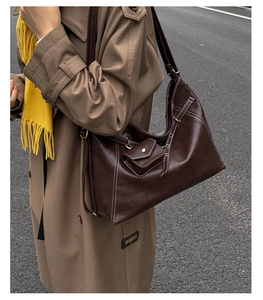 Detail of dark brown tote bag with white contrast stitching and a small hanging pouch