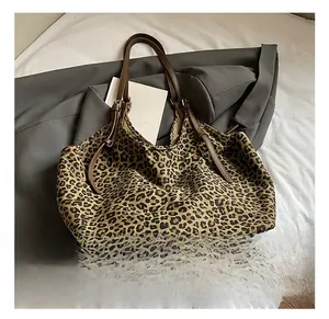 Close-up of leopard print tote bag fabric with dark brown shoulder straps and metal hardware