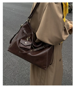 Detail of dark brown tote bag with white contrast stitching and a small snap pouch