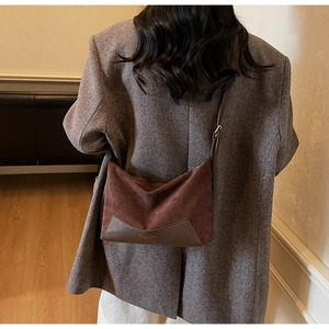 Detail of suede and leather patchwork shoulder bag with adjustable strap and logo
